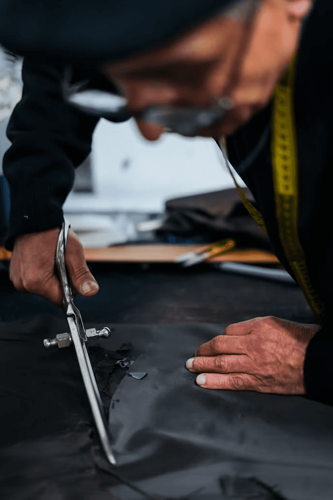 A tailor leaning in close to check the cut of a dark garment