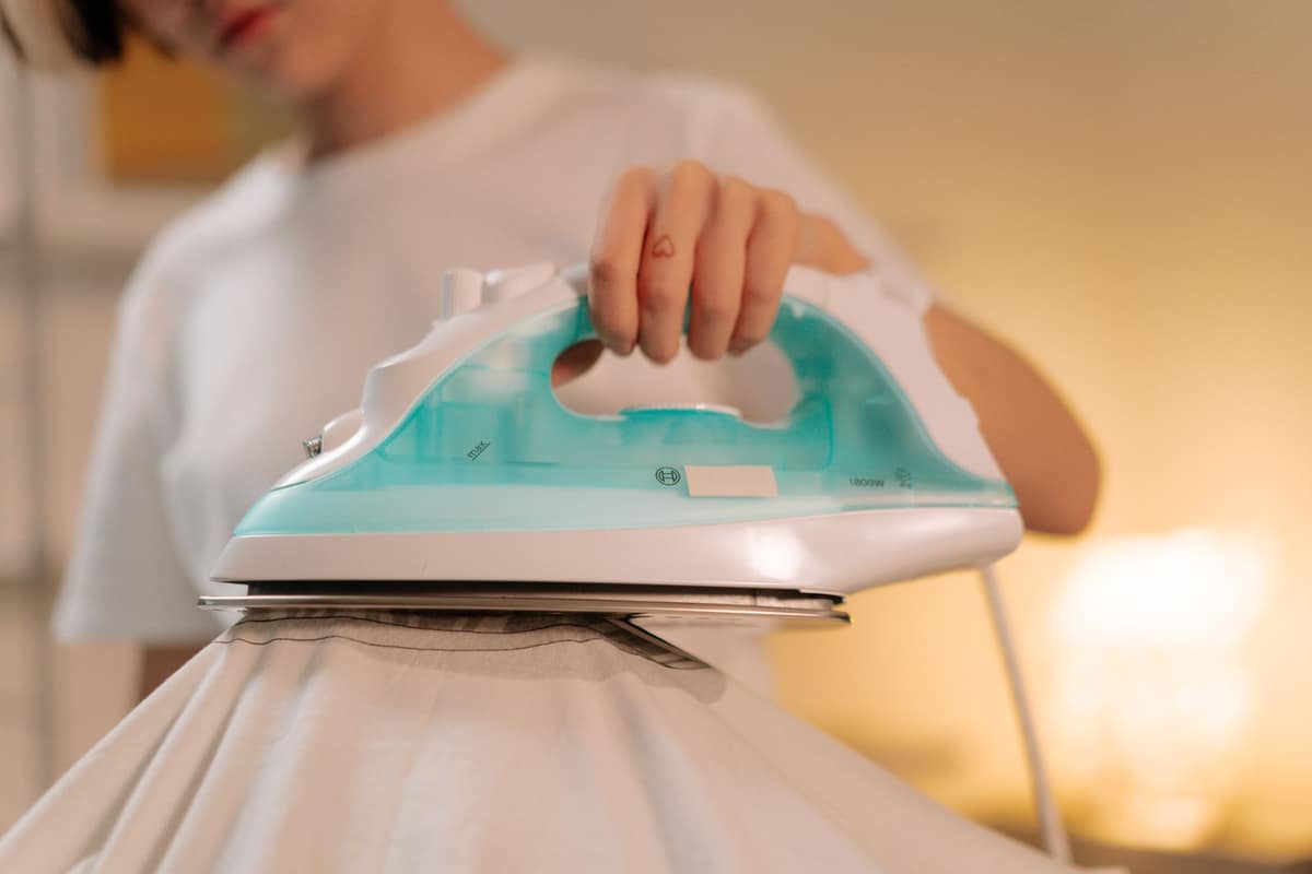 A steam iron pressing a pale garment in warm light