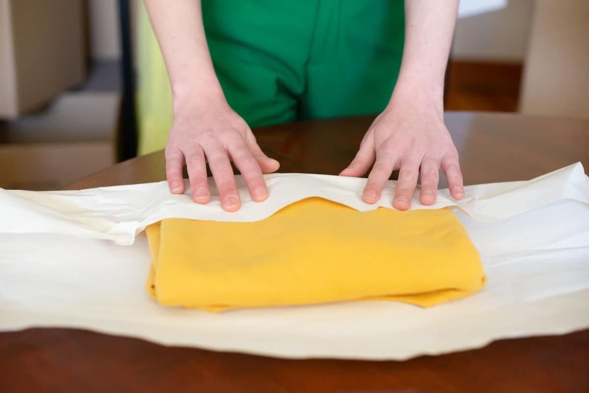 A folded garment being wrapped in tissue paper, ready to be sent