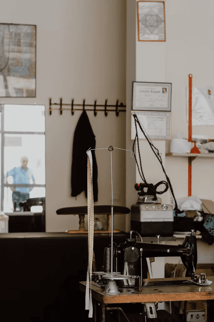 The workshop: a sewing machine, pressing table and a tape measure hanging beside it